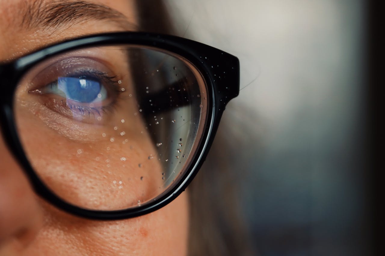 our-story-01 Detailed close-up of a person's eye reflecting through eyeglasses.