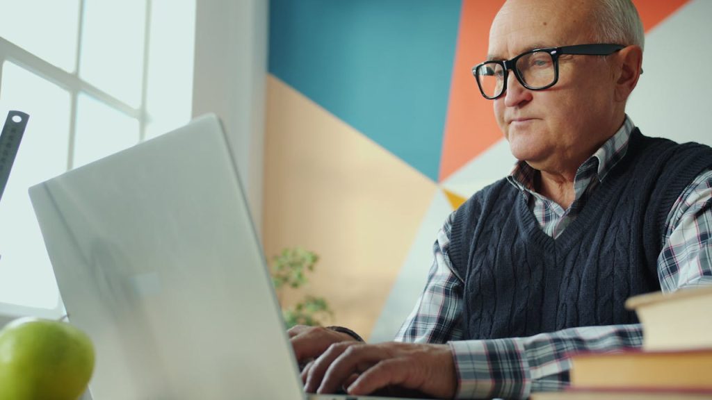 Crafting Captivating Headlines: Your awesome post title goes here Elderly man focused on his laptop in a stylish, colorful office environment.